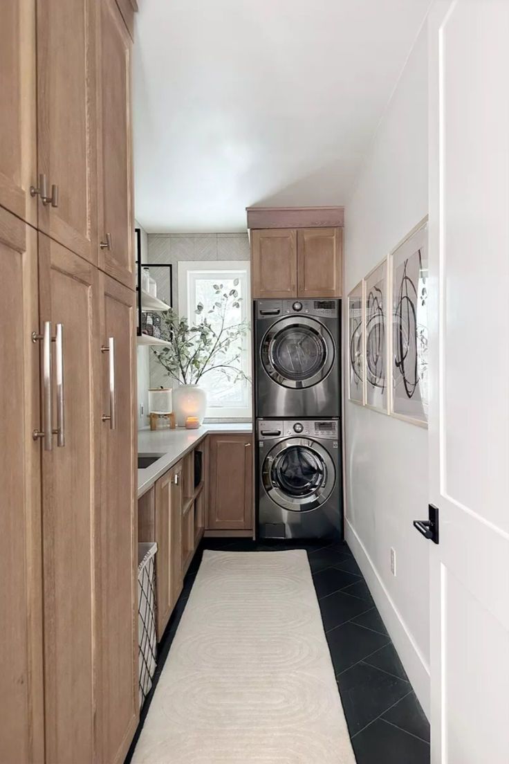 a washer and dryer are in the middle of a long hallway with wood cabinets