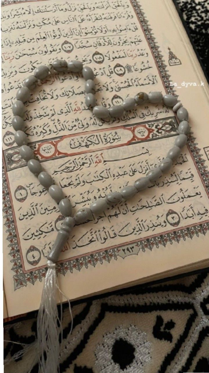 an open book with a tasseled rosary on top of it next to a black and white rug