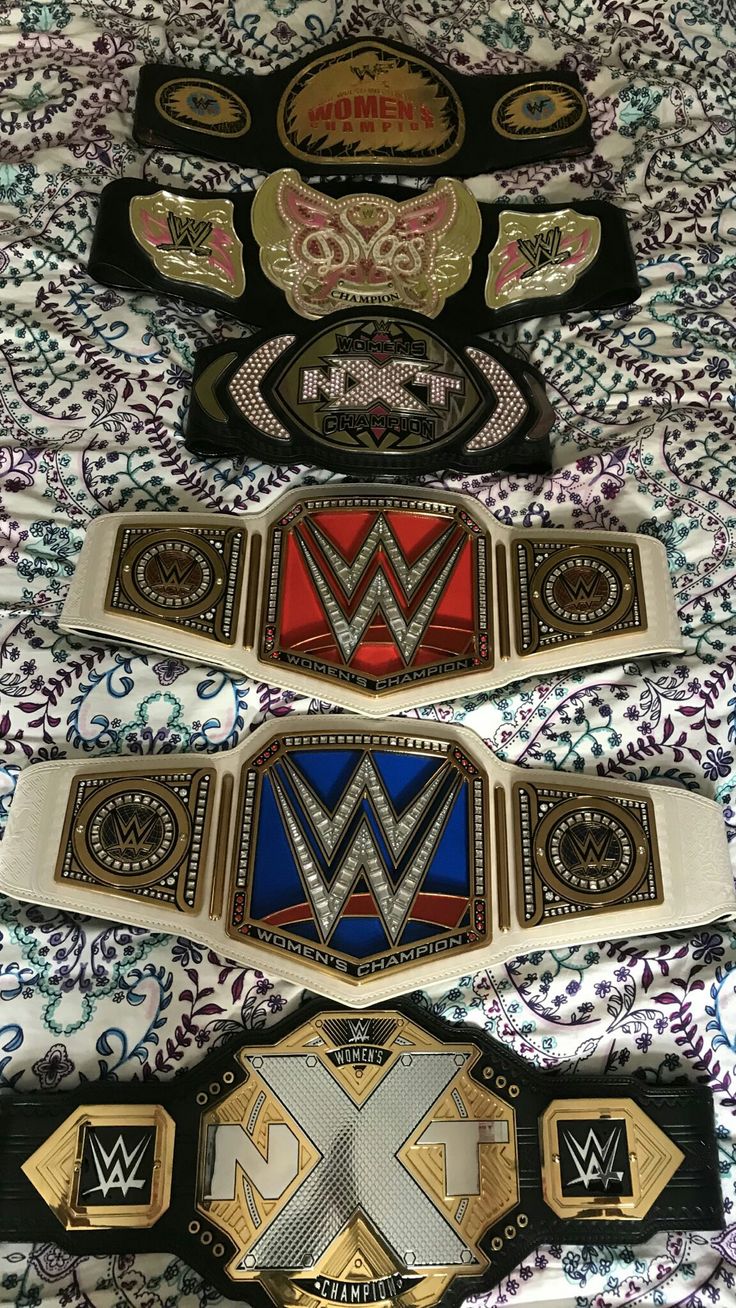 three wwe belts laying on top of a bed