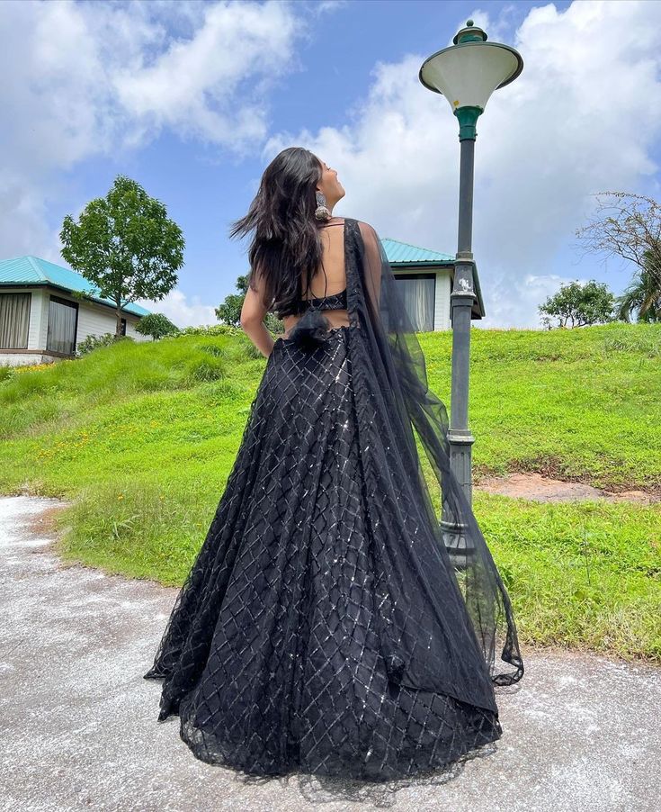 a woman standing next to a lamp post wearing a black dress and headpieces