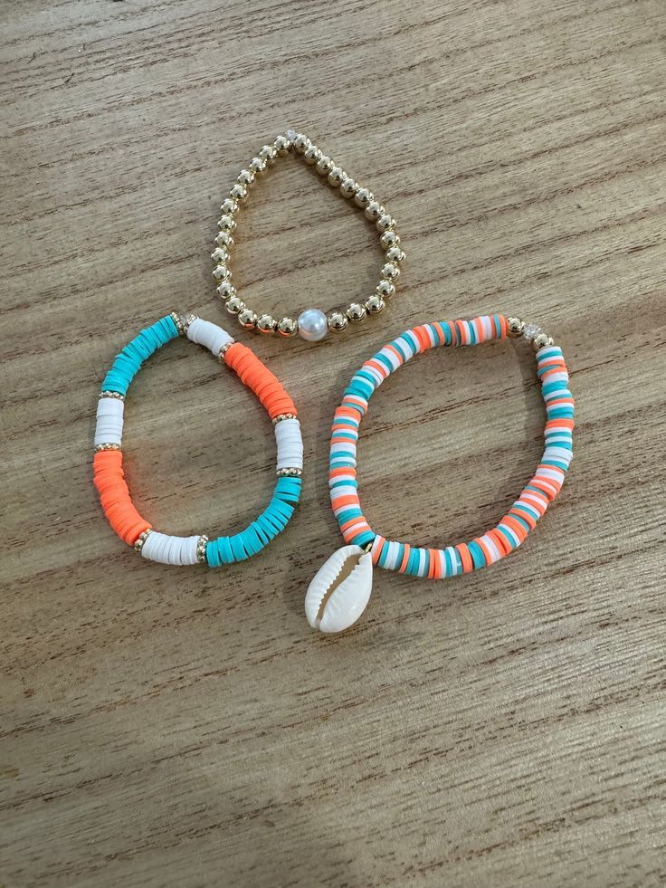 two bracelets on a wooden table one with shell and the other with beaded beads