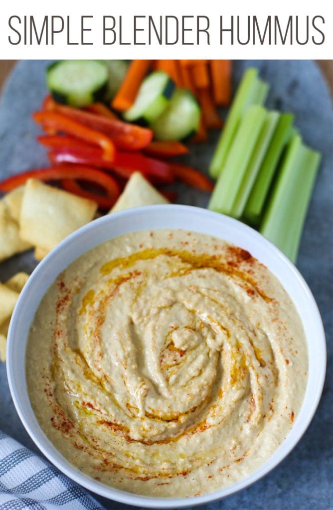 a white bowl filled with hummus next to sliced celery and carrots