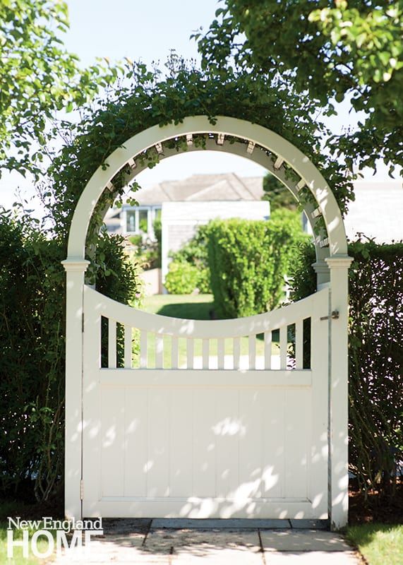 a white garden gate with an arch over it