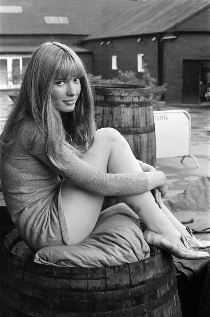 a woman sitting on top of a barrel next to a building