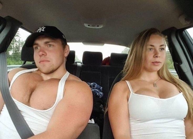 two people sitting in the back seat of a car, one is wearing a tank top