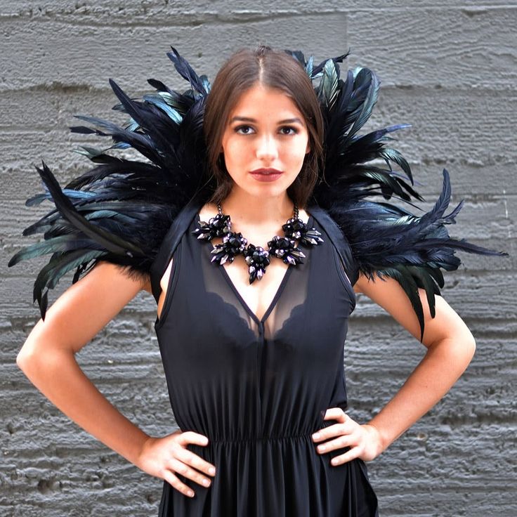 a woman in a black dress with feathers on her shoulders