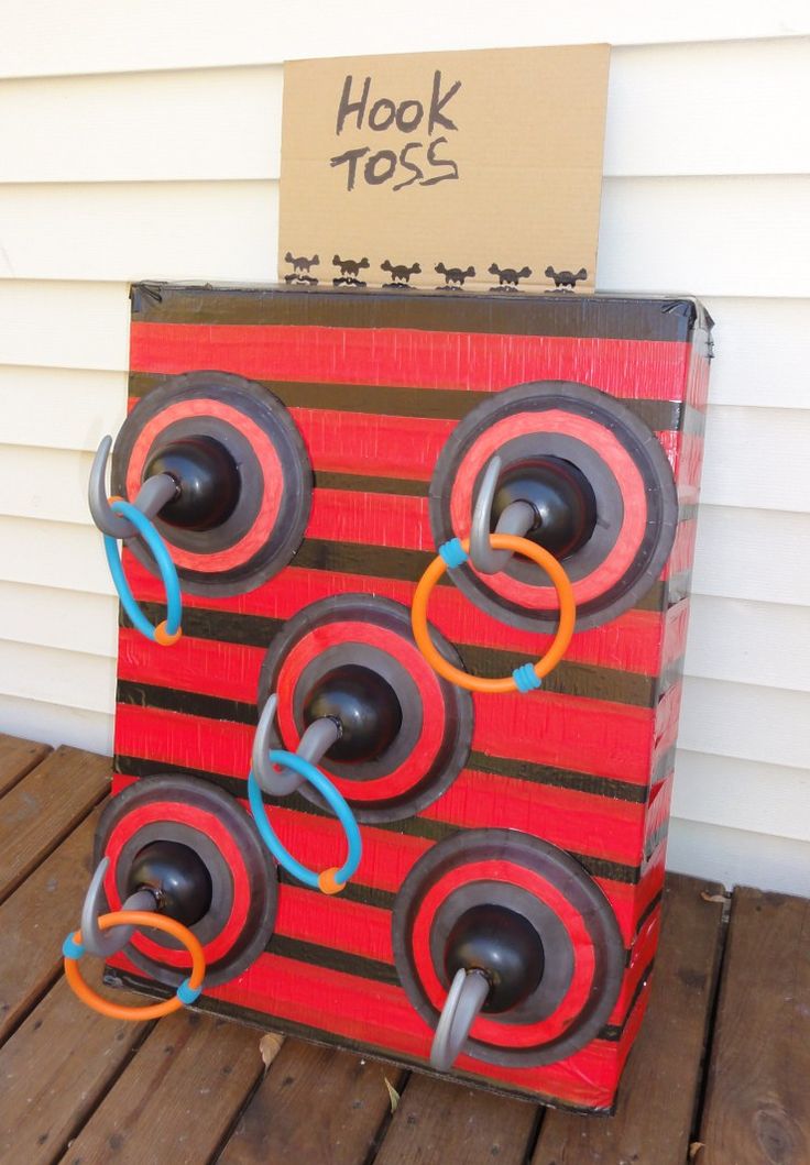 a cardboard box with rings on it sitting on a wooden floor next to a sign that says hook toss