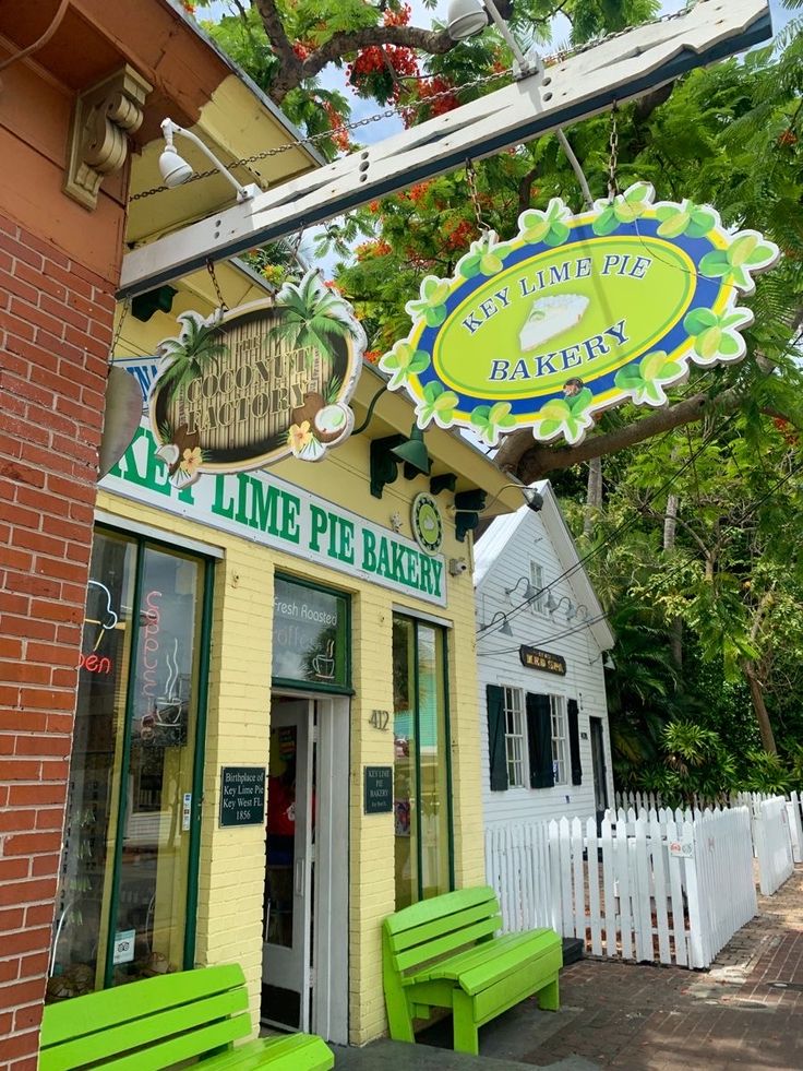 the lime pie bakery is located on the side of the building and has green benches in front of it