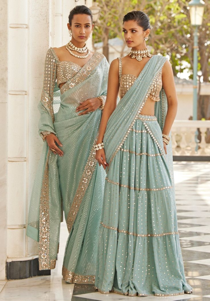 Introducing the ethereal powder blue tiered saree with a glam sleeveless blouse. This stunning saree features delicate powder blue georgette adorned with real hand-cut mirror embroidery. The multi-tier design adds volume and movement, creating a mesmerizing silhouette. Paired with a stylish, modern cut sleeveless blouse embellished with hand-cut mirrors, this set exudes glamour. Ideal for Mehendi or Sangeet ceremonies. Composition : Saree & Blouse - Georgette Care: Dry Clean Only and Vacuum Storage This product can be customized for sleeves, length and colour Delivery : 6-8 weeks as the product is hand crafted. Check Size Guide or choose MySize for free customisation (All Sizes above XL can be made at 15% additional cost) For more information and sizes please contact fabiliciousfashion@gma Saree With Sleeveless Blouse, Blue Organza Saree, Mirror Blouse, Sky Blue Saree, Vani Vats, Sequins Saree, Reception Outfits, Full Sleeve Blouse, Organza Lehenga