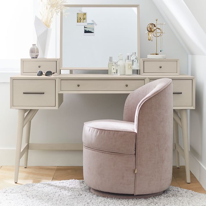 a chair sitting in front of a desk with a mirror and drawers on top of it