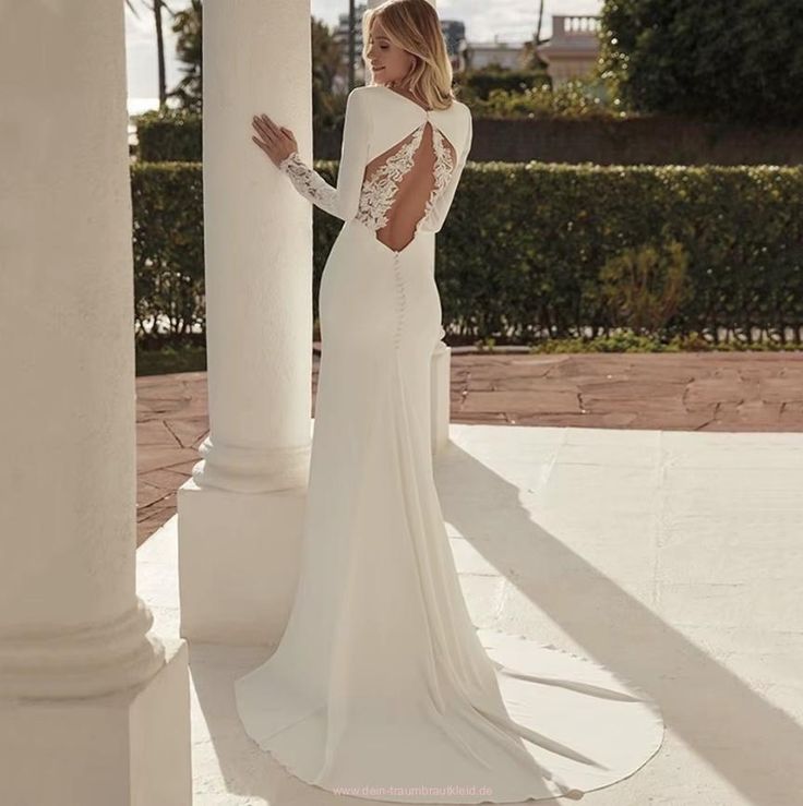 a woman in a white dress standing next to pillars and looking off into the distance