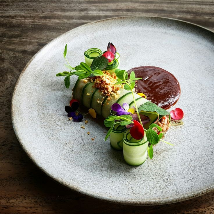 a white plate topped with cucumbers and sauce on top of a wooden table