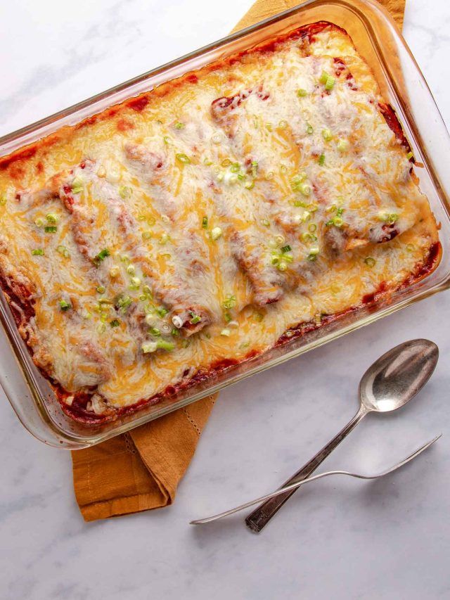 a casserole dish with meat, cheese and vegetables in it next to a spoon