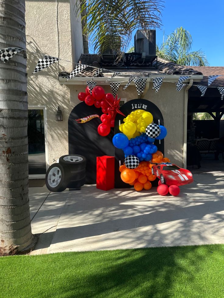 an outdoor birthday party with balloons and race cars