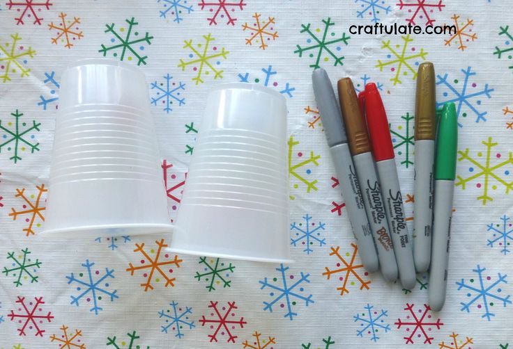 four markers and three cups sitting on a table with snowflakes in the background