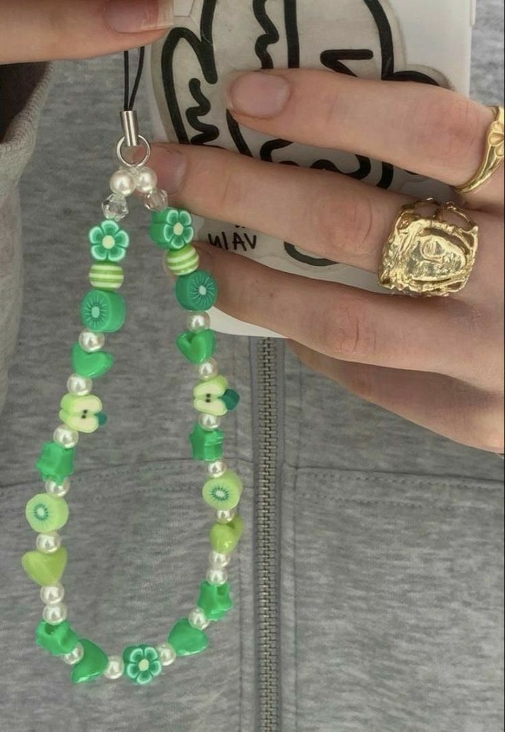 a close up of a person holding a cell phone and wearing a necklace with beads