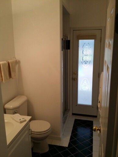 a white toilet sitting next to a sink in a bathroom under a shower stall with a glass door