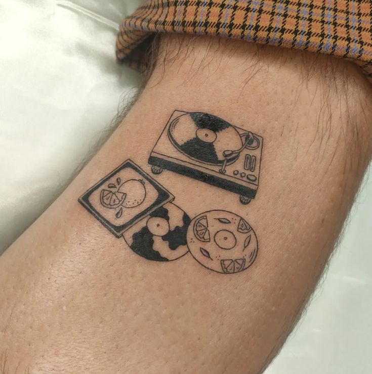 a man with a tattoo on his arm has a record player and video game controllers