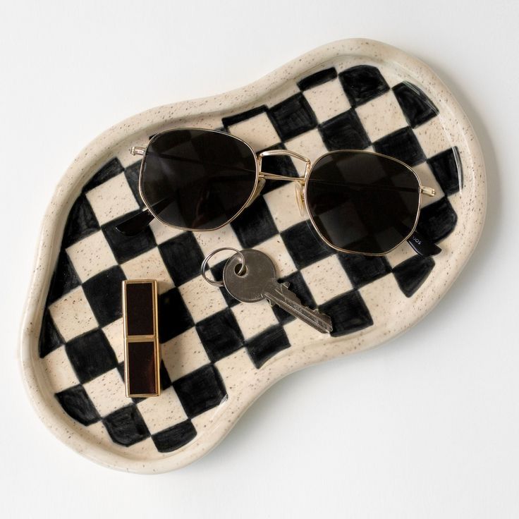 two pairs of sunglasses sitting on top of a black and white checkerboard tray