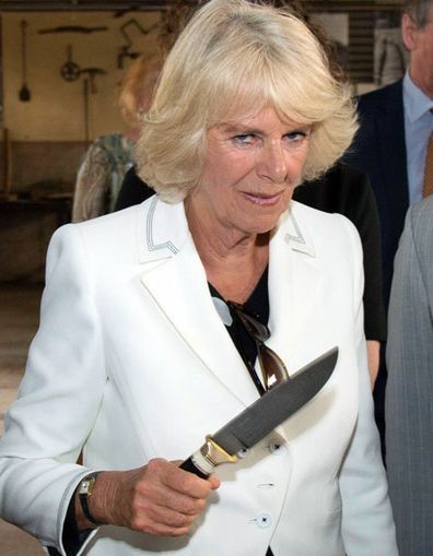 the woman is holding a large knife in her hand and wearing a white suit jacket