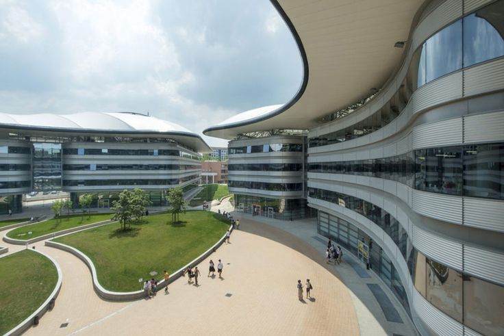 an aerial view of people walking around in front of a large building with curved windows