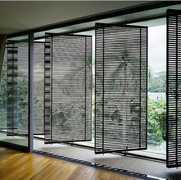 an open room with wooden flooring and sliding glass doors that have black slats on them