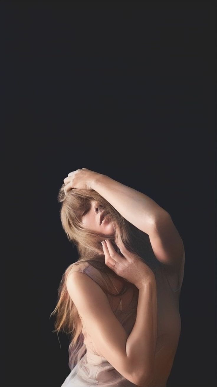 a woman in a white dress holding her head with one hand and looking off to the side