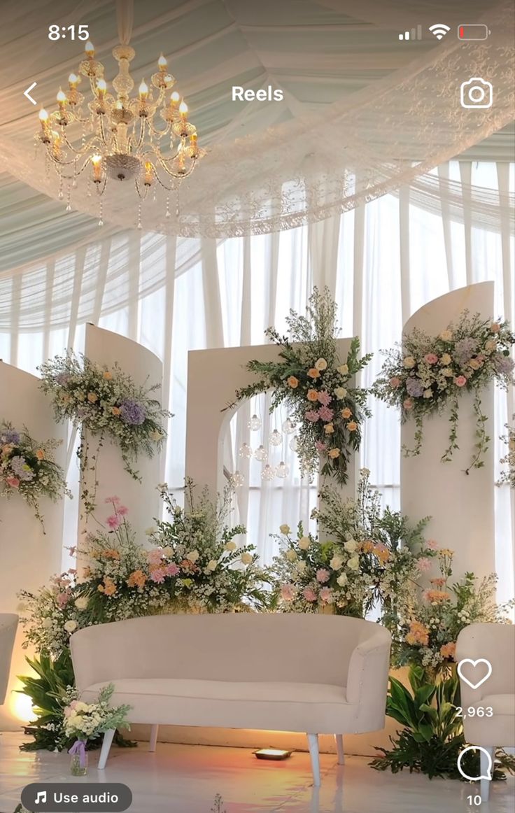 a couch sitting under a chandelier covered in flowers