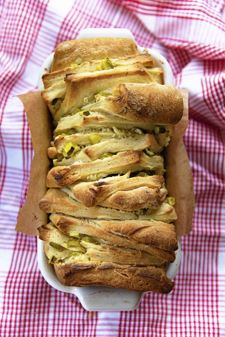 a white dish filled with bread on top of a red and white checkered table cloth