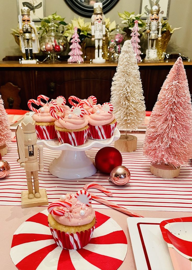 a table topped with cupcakes covered in pink frosting and candy canes