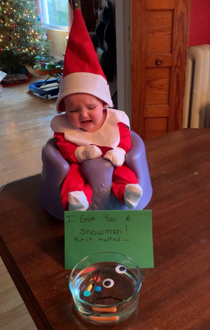 a baby wearing a santa hat sitting on top of a table