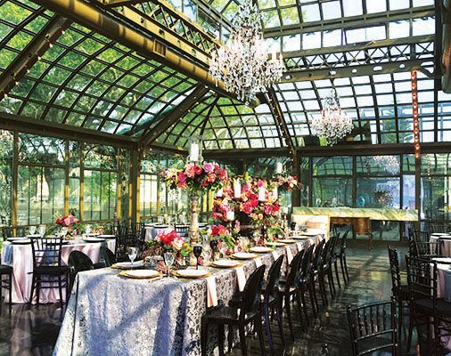 an indoor dining area with tables and chairs, chandelier and flowers in vases