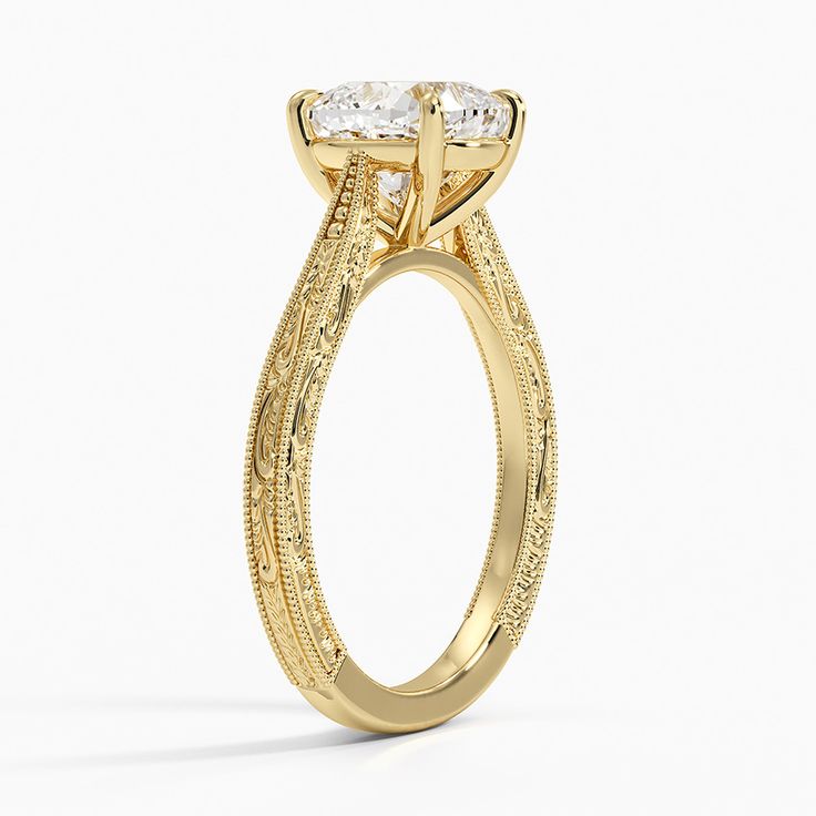 a yellow gold engagement ring with an oval cut diamond in the center and intricate filigrees on the sides