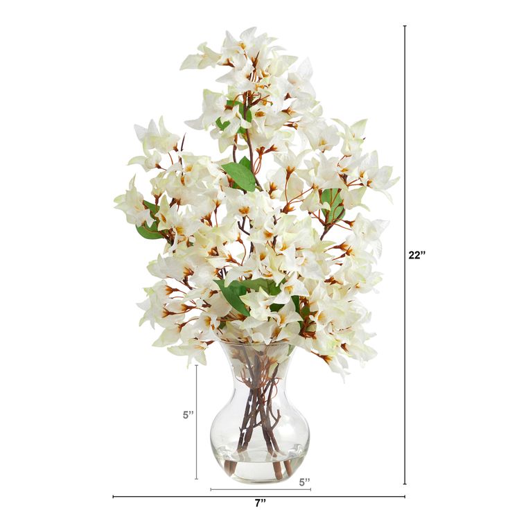 a vase filled with white flowers sitting on top of a table next to a ruler