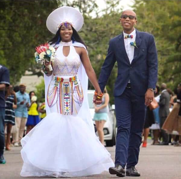 a man and woman walking down the street in wedding attire with hats on their heads