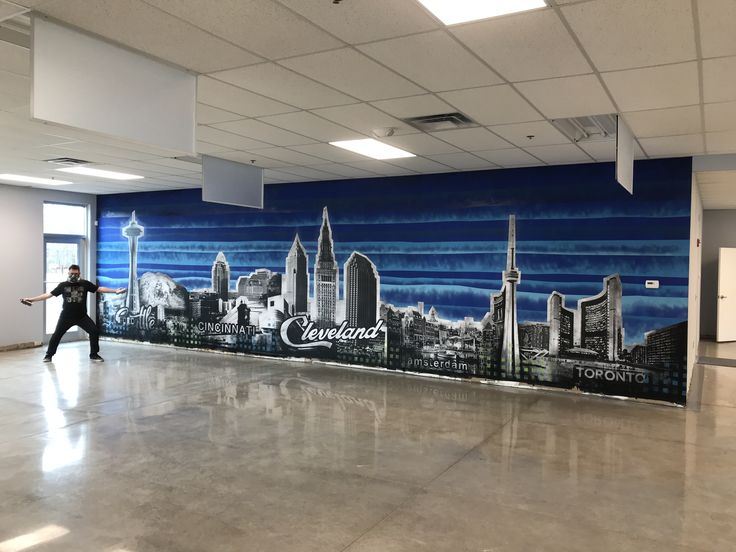 a man is dancing in front of a wall mural that has a cityscape on it