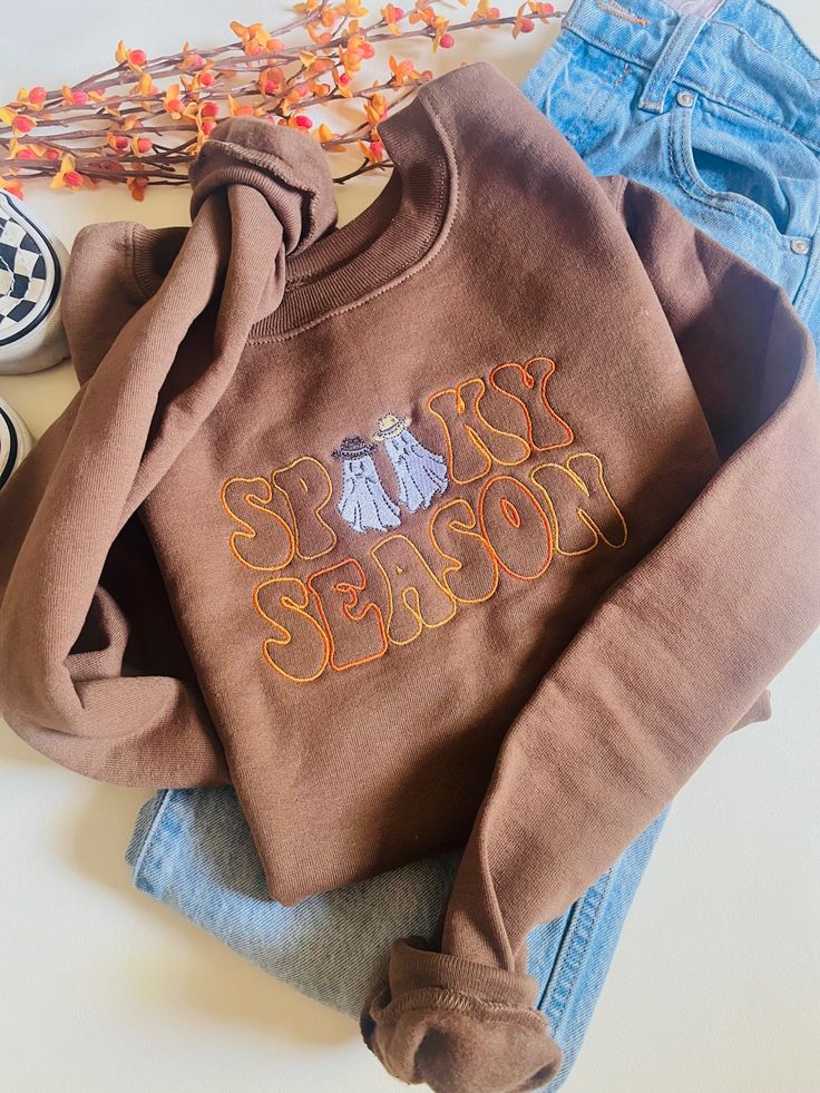 The cutest new edition to the shop! A Spooky Season Western Ghosts Embroidered design on a Hanes Eco Smart/ Gildan Crewneck. Cute Floral Embroidery Fall Tops, Retro Embroidered Sweatshirt For Fall, Brown Fall Sweatshirt With Embroidered Logo, Brown Sweatshirt With Embroidered Logo For Fall, Trendy Tops With Custom Embroidery For Fall, Retro Tops With Embroidered Logo For Fall, Cute Embroidered Text Tops For Fall, Cute Tops With Embroidered Text For Fall, Retro Embroidered Fall Tops