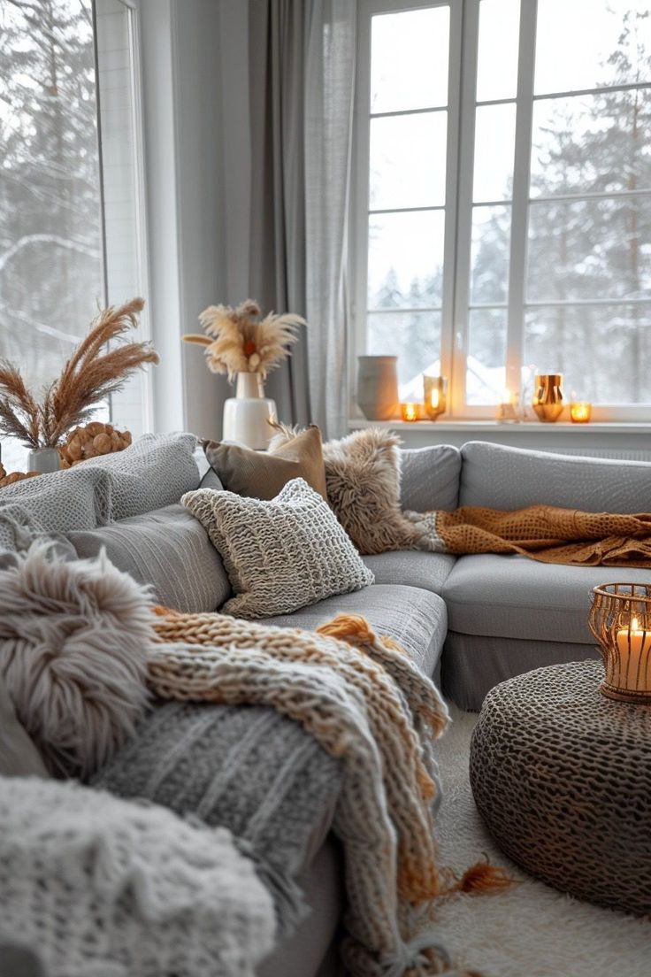 a living room filled with lots of furniture next to a window covered in blankets and candles