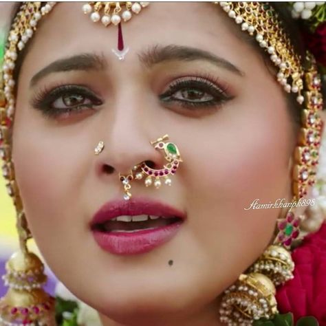 a close up of a woman with makeup and jewelry on her face, looking at the camera