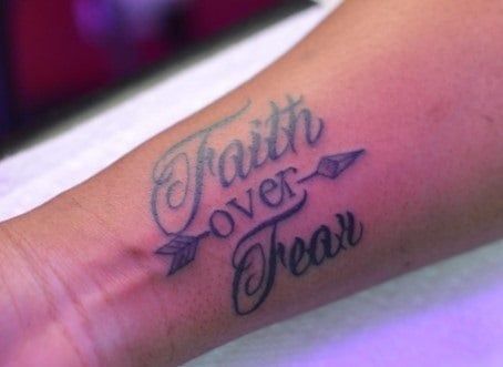 a person with a tattoo on their arm that says faith over them and an arrow