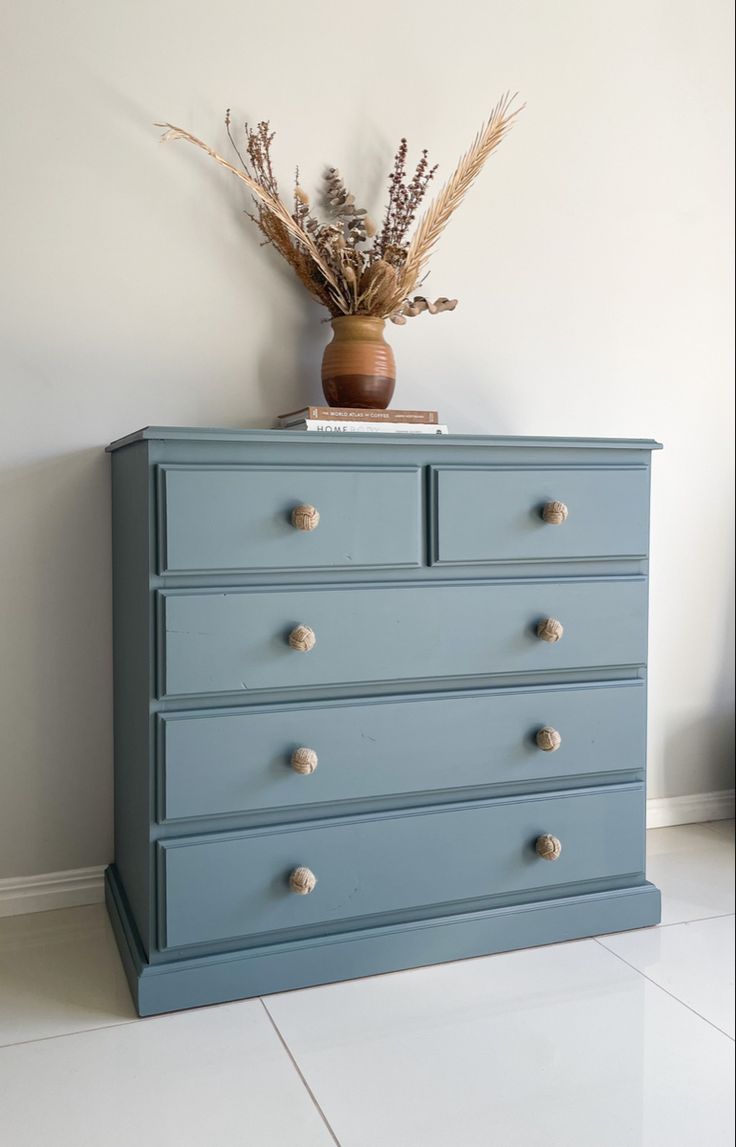 a blue dresser with some dried plants on top