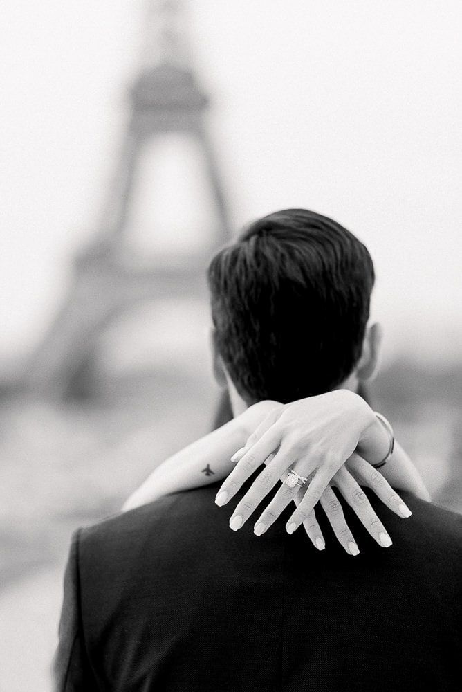 a man and woman embracing in front of the eiffel tower