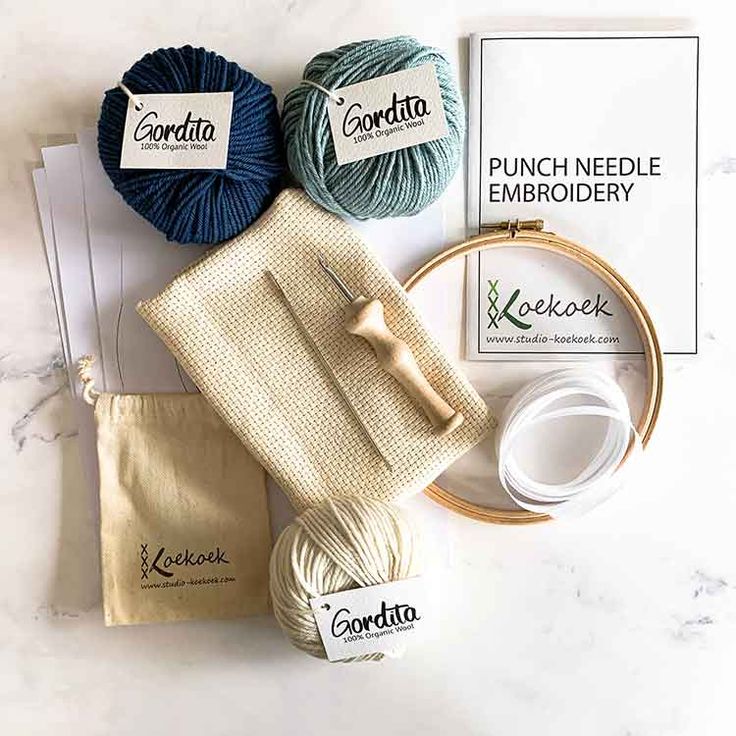 the contents of a crochet kit laid out on a marble counter top with yarn, scissors and thread