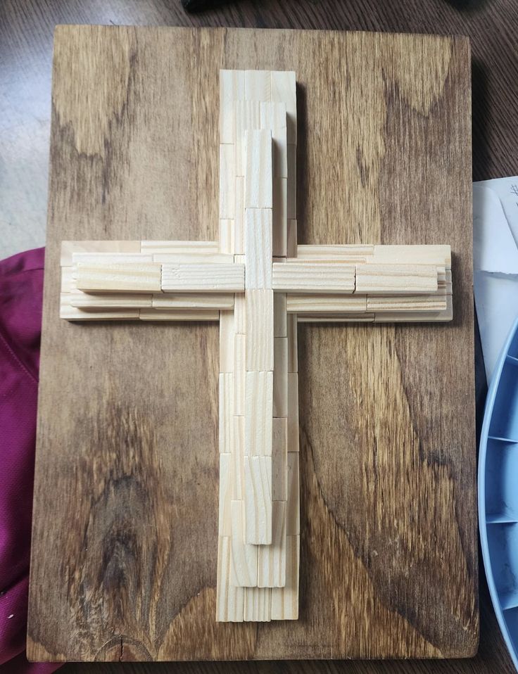 a wooden cross sitting on top of a table next to a blue plate and knife