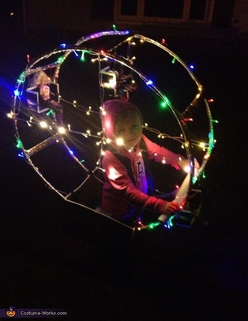 a man is spinning around with christmas lights on his body and holding an object in the air