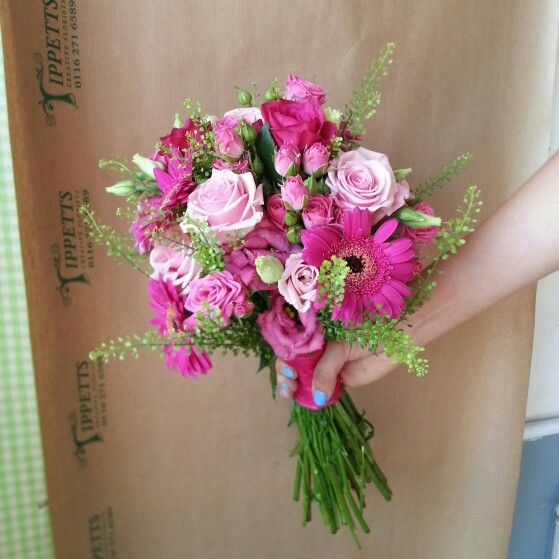 a person holding a bouquet of pink flowers in their left hand and the box behind them