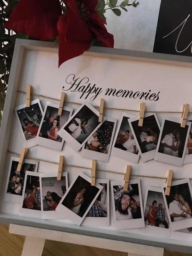 there are many pictures hanging on the clothes pegs with some flowers in the background