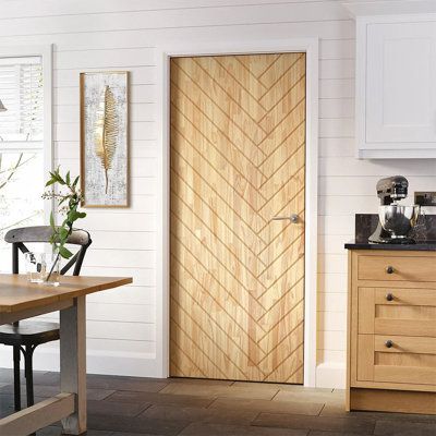 a kitchen with white walls and wooden floors, an oak door is open to the dining room