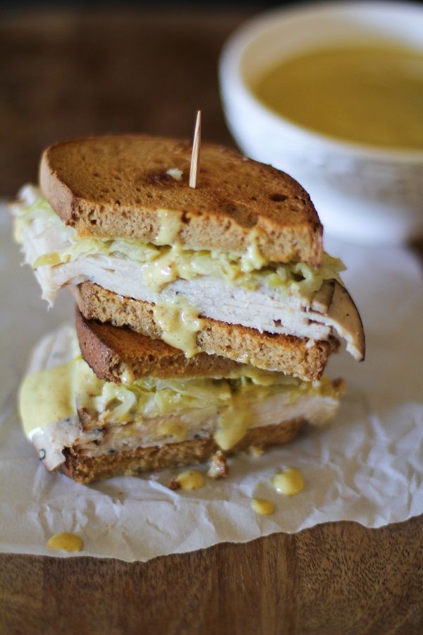 a sandwich cut in half sitting on top of a piece of paper next to a bowl of soup