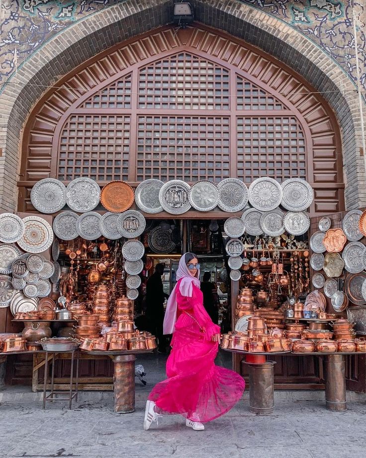 a woman standing in front of a store with lots of plates on display